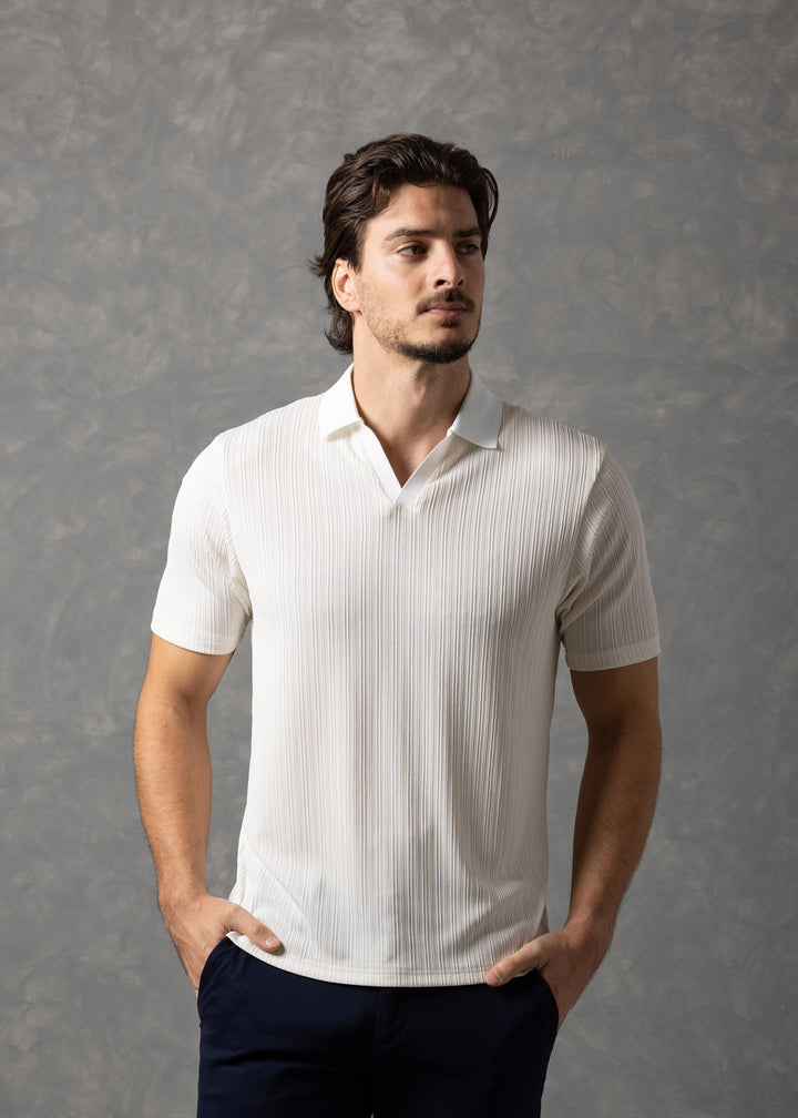 Man wearing a white shirt and dark pants against a gray background