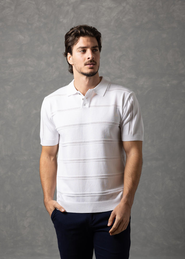 Man wearing a white striped polo shirt and dark pants against a gray background