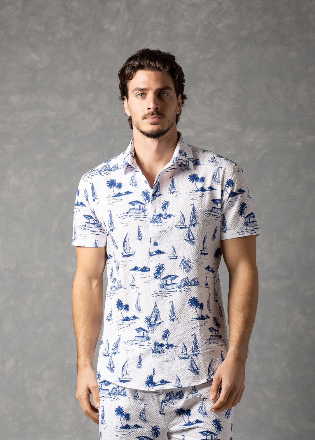 Man wearing a white shirt and shorts with blue patterns against a gray background